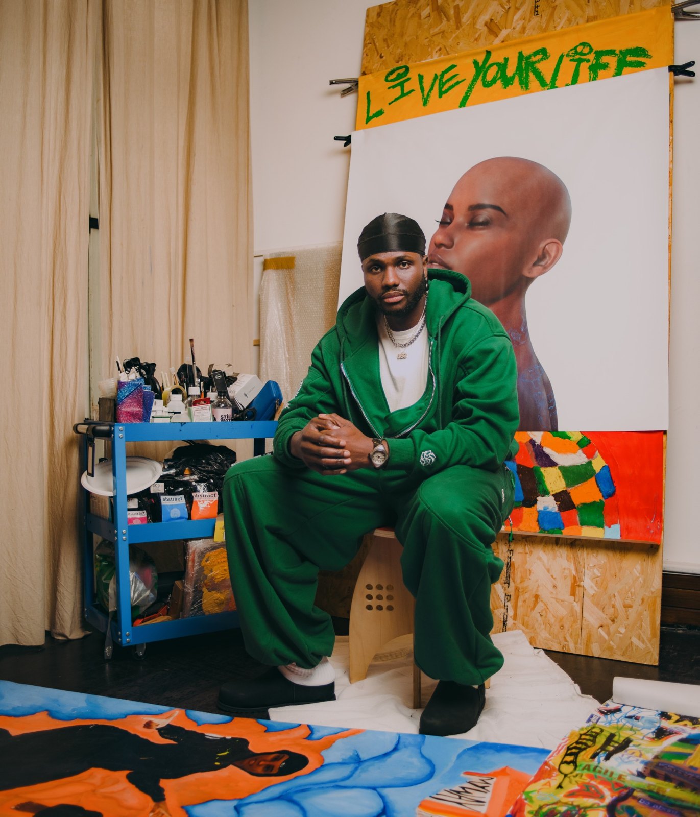 Artist in green in front of his painting