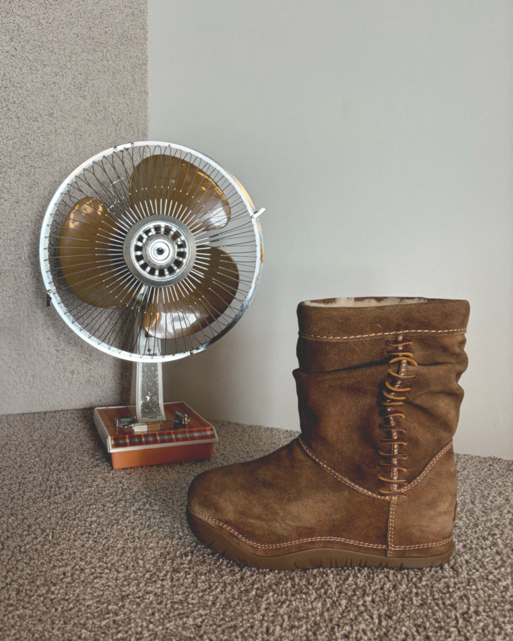 UGG boot still life beside a vintage fan